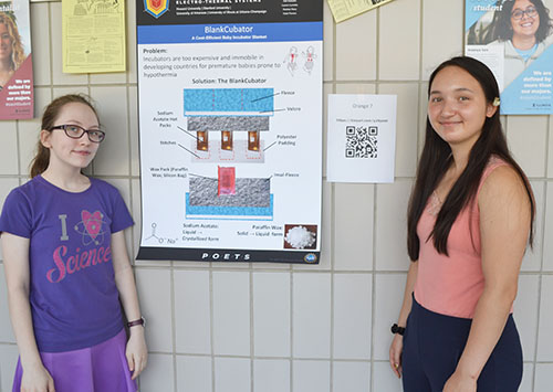 Uni High students Katie Powers and Lauren Mettlett by their poster.