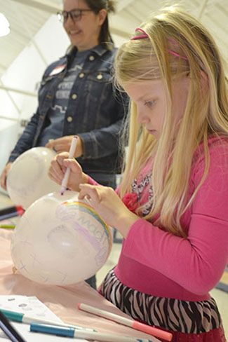 A young visitor works on her fingerprint balloon.
