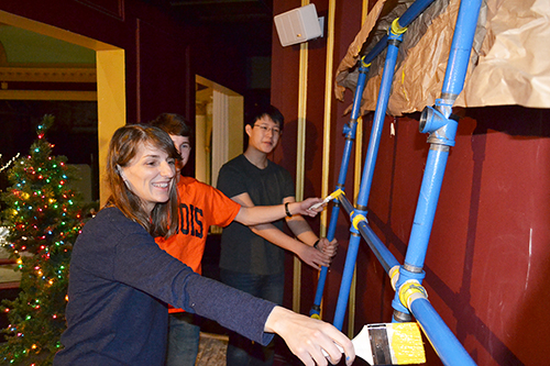 Denos (left) and two of her students paint the scaffolding for the wind maze.