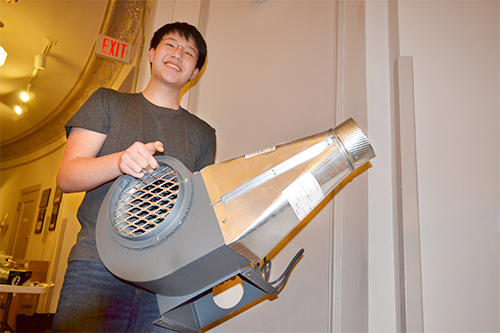 Uni student prepares to install the blower motor in the brightly painted box they constructed to house it.