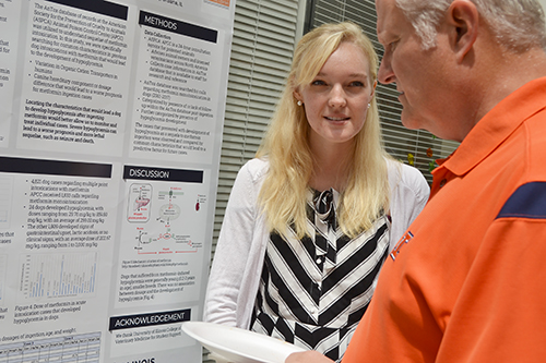 Jessica Kerr discusses her research with a visitor to SRTP's end-of-summer poster session.